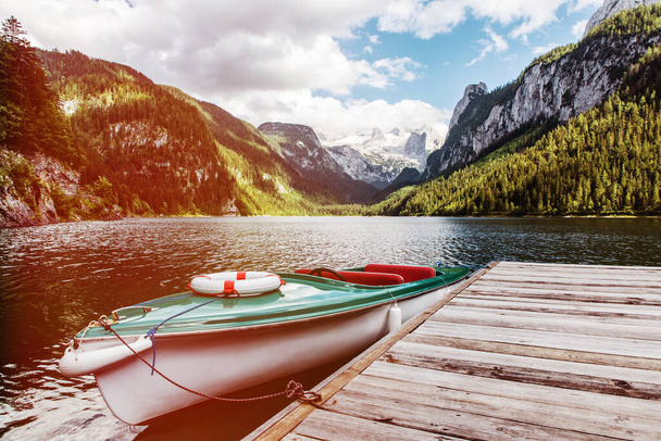 Красивый пейзаж озера Госаузи с горами Дахштайн, лодкой, лесом, облаками и отражениями в воде в австрийских Альпах. Зальцкаммергут. - Фото, изображение