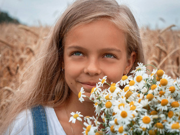 dívka s dlouhými vlasy na poli s kyticí sedmikrásek - Fotografie, Obrázek