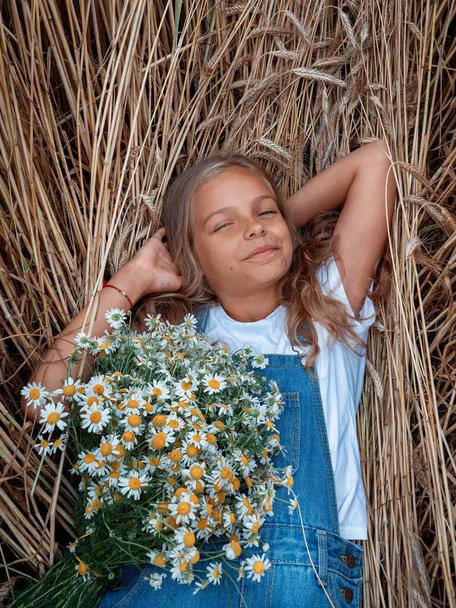 meisje met lang haar in een veld met een boeket madeliefjes - Foto, afbeelding