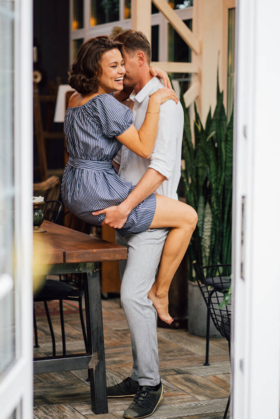 view through door from street to couple hugging near wooden table. - Foto, immagini