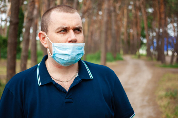 健康、パンデミックおよび安全の概念森林背景、屋外での保護のための顔保護医療マスクが低いヨーロッパの男性. - 写真・画像
