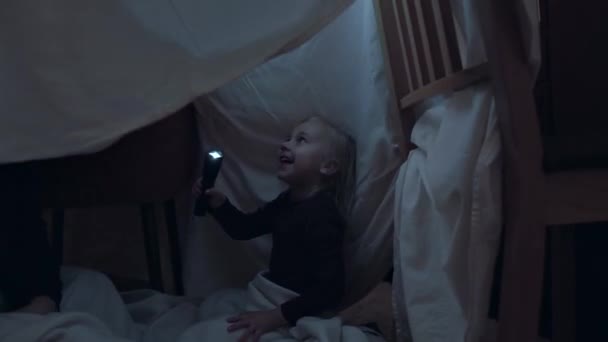 Happy mother and daughter play in a toy wigwam with a flashlight - Footage, Video