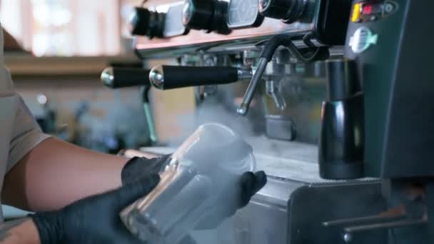 young barista in gloves processes transparent glass glasses for cocktails with help of hot steam using professional coffee machine, small business - Кадры, видео