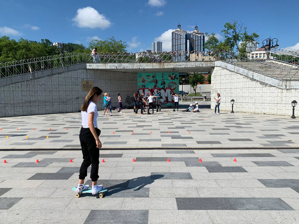 Vladivostok, Russia,  July, 13, 2020. Vladivostok, a girl rides a skateboard next to the viewport "Bridge of love" on Tsarevich Nicholas embankment - Foto, Imagem