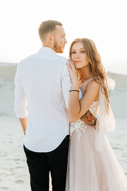 Love Story of a beautiful couple in a pink wedding luxury dress with a bouquet in the Sahara desert, sand, dunes - Fotografie, Obrázek