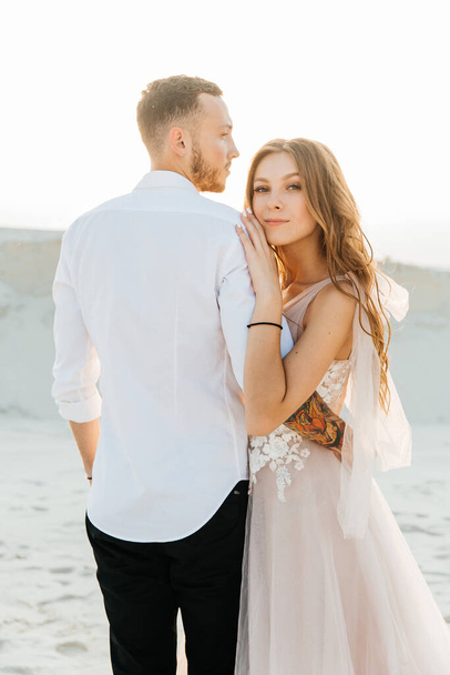 Love Story of a beautiful couple in a pink wedding luxury dress with a bouquet in the Sahara desert, sand, dunes - Photo, image
