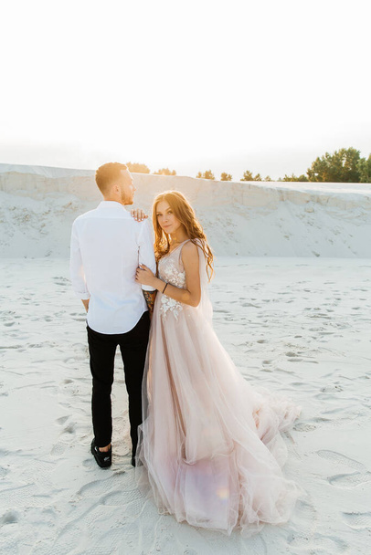 Love Story of a beautiful couple in a pink wedding luxury dress with a bouquet in the Sahara desert, sand, dunes - Φωτογραφία, εικόνα