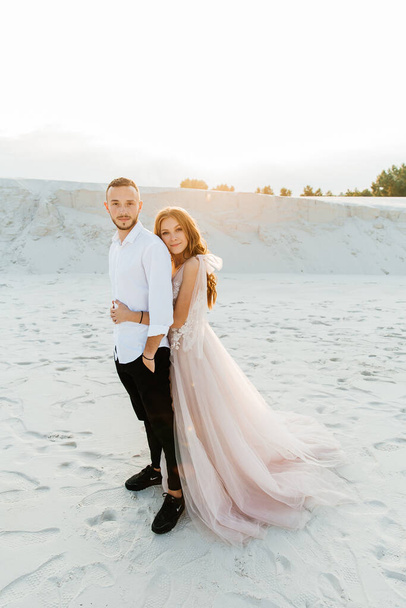 Love Story of a beautiful couple in a pink wedding luxury dress with a bouquet in the Sahara desert, sand, dunes - Photo, Image