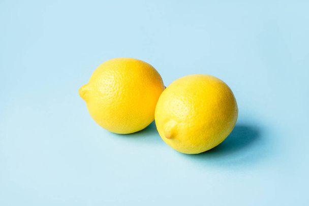 Two ripe lemons on a blue background. - Zdjęcie, obraz