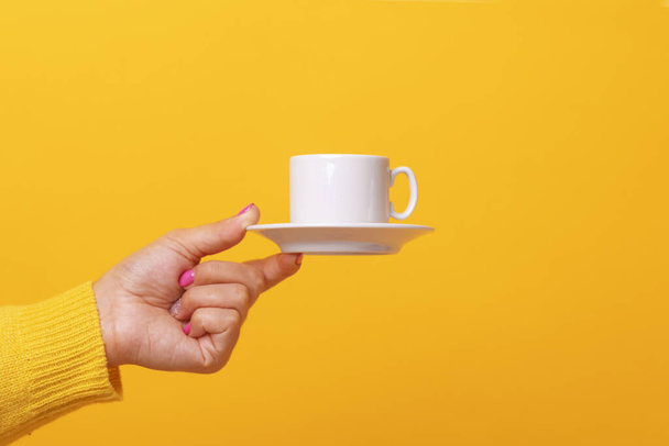 coffee cup in hand over yellow background - Φωτογραφία, εικόνα