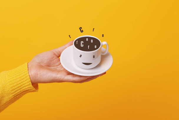 hand holding coffee cup over yellow background - Zdjęcie, obraz