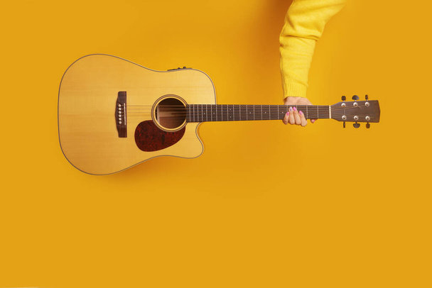 gitara w dłoni na żółtym tle, makieta obraz - Zdjęcie, obraz
