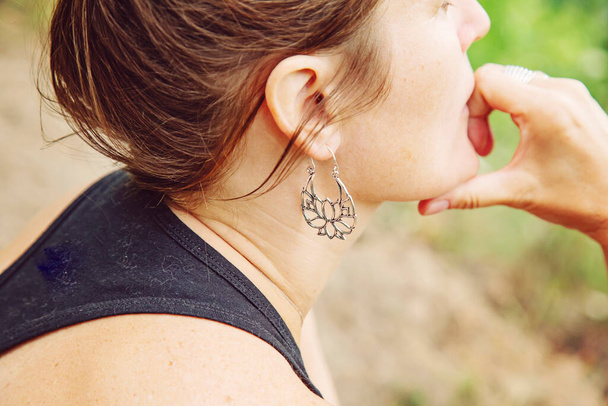 Outdoor portrait of a woman wearing silver metal earrings  - Photo, Image