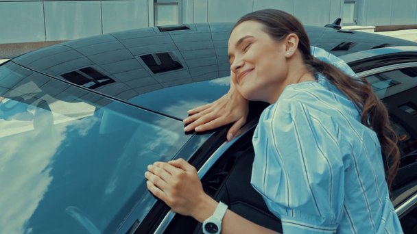 šťastná mladá žena se zavřenýma očima s úsměvem při objímání vlastní auto  - Záběry, video