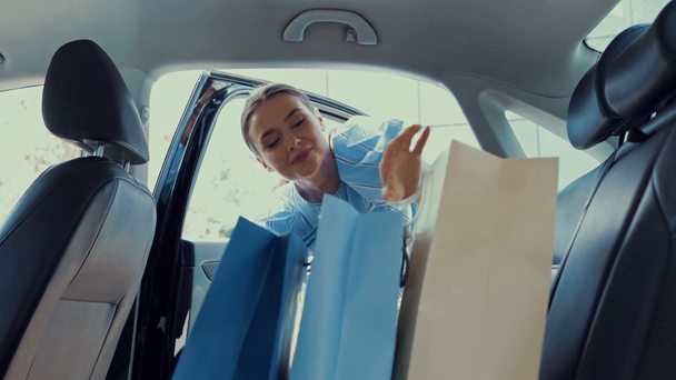 boldog nő nyitó autó ajtó és üzembe bevásárló táskák a hátsó ülésen  - Felvétel, videó