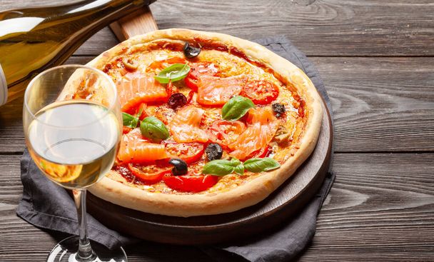 Délicieuse pizza maison aux fruits de mer avec tomates de jardin, fromage, saumon et basilic. Avec vin blanc et espace de copie - Photo, image