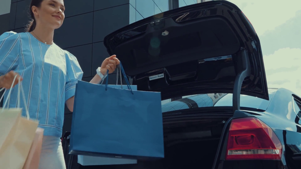 happy woman taking shopping bags from car trunk - Záběry, video