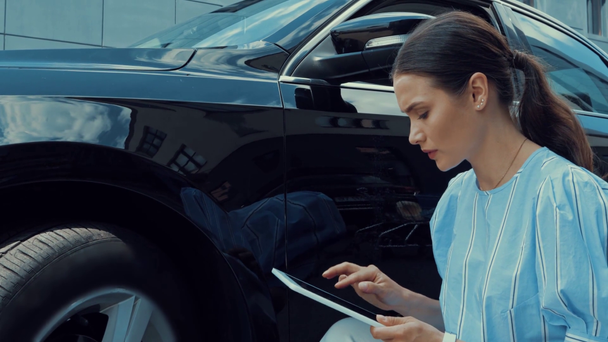 серйозна жінка торкається автомобіля і використовує цифровий планшет
 - Кадри, відео