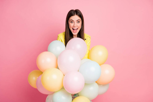 Photo of funny charming lady hold hands many air balloons festive event birthday party open mouth wear trend yellow leather jacket isolated pastel pink color background - 写真・画像