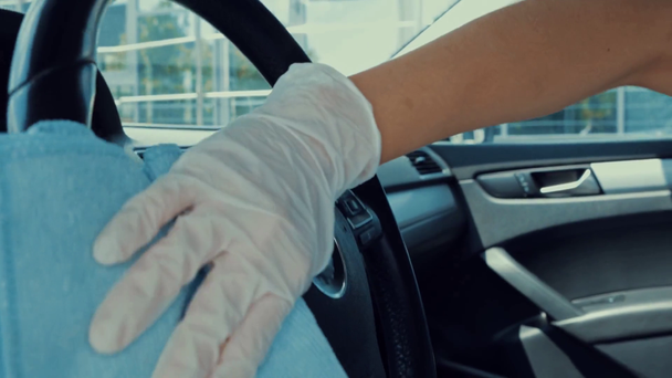bijgesneden beeld van vrouw in latex handschoenen desinfecteren stuurwiel in auto - Video
