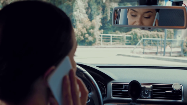 mulher feliz sentado no carro, falando no smartphone e olhando no espelho retrovisor
 - Filmagem, Vídeo