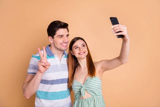 Portrait of his he her she nice attractive lovely pretty cheerful cheery couple friends friendship taking making selfie showing v-sign isolated over beige pastel color background - Foto, afbeelding