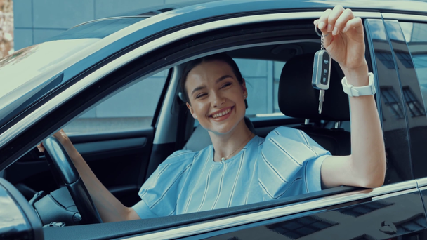 mujer feliz sentada en el coche en el lugar de los conductores y mostrando la llave del coche
 - Metraje, vídeo