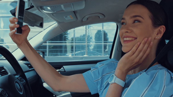 счастливая женщина делает селфи на смартфоне на месте водителя в машине - Кадры, видео