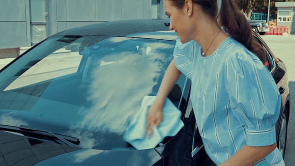 Çekici bir kadın arabanın ön camını paçavrayla siliyor. - Video, Çekim