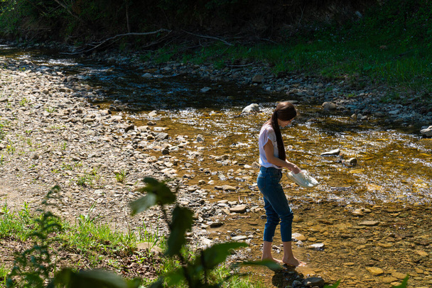 若いですブルネット裸の女性は山の川に沿って歩く - 写真・画像