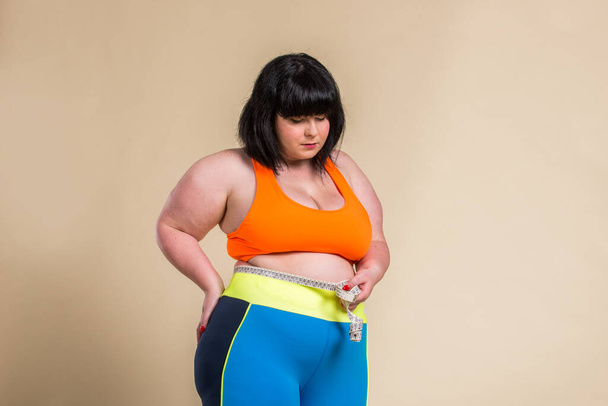 Pretty oversize woman wearing sportswear posing in studio - Beautiful girl accepting body imperfection, beauty shots in studio - Concepts about body acceptance, body positivity and diversity - Photo, Image