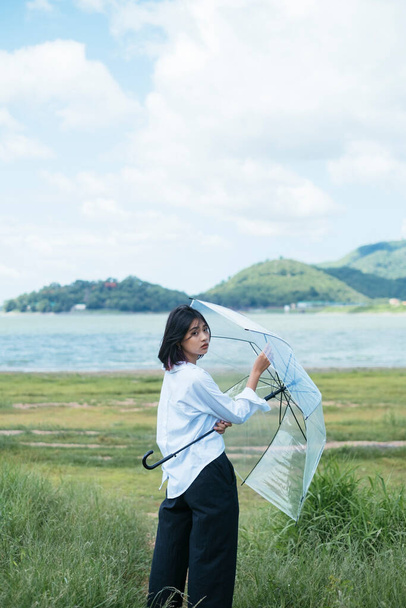 fiatal ázsiai nő kezében átlátszó esernyő, repülő esernyő. - Fotó, kép