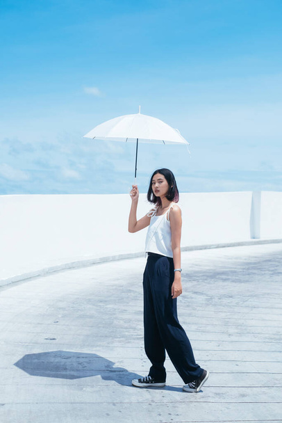 Asian woman on white shirt holding white umbrella in sunny day. - Фото, изображение