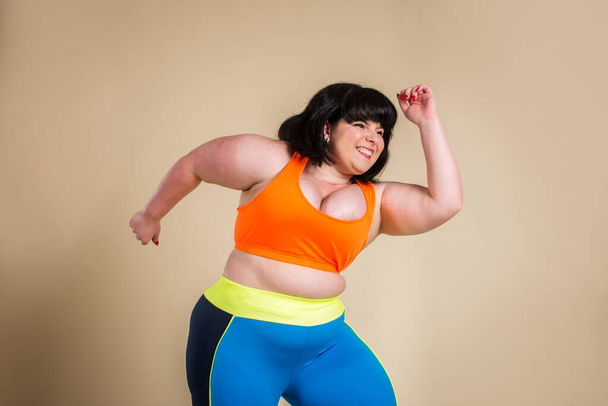 Pretty oversize woman wearing sportswear posing in studio - Beautiful girl accepting body imperfection, beauty shots in studio - Concepts about body acceptance, body positivity and diversity - Foto, Imagem