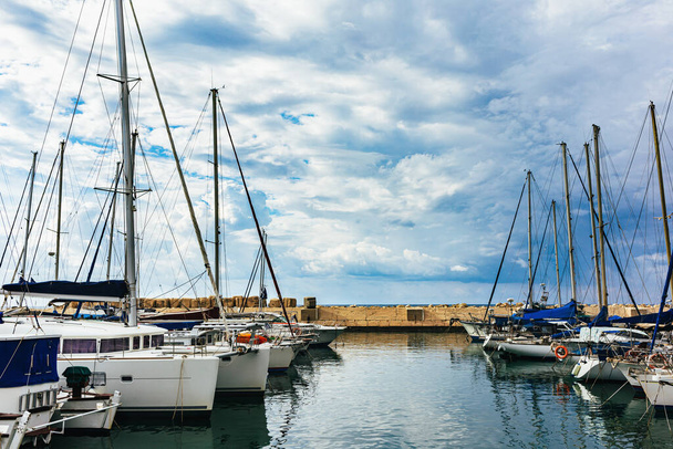 Vitorláshajók az ősi Jaffa-k régi kikötőjében. Tel Aviv, Izrael. Gyönyörű felhős ég.. - Fotó, kép