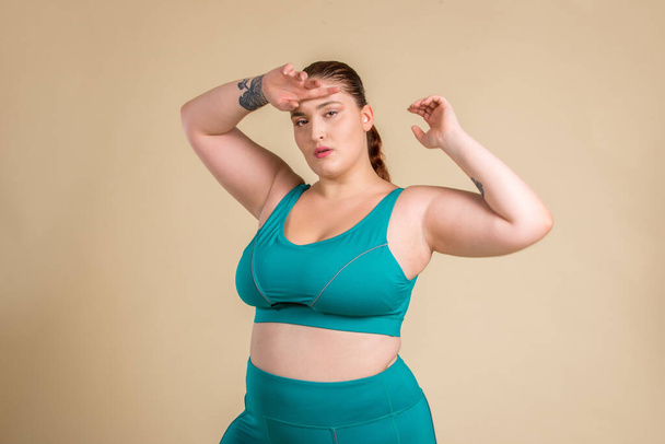 Pretty oversize woman wearing sportswear posing in studio - Beautiful girl accepting body imperfection, beauty shots in studio - Concepts about body acceptance, body positivity and diversity - Foto, afbeelding