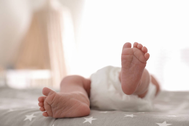 Cute little baby lying on bed at home, closeup of legs - 写真・画像