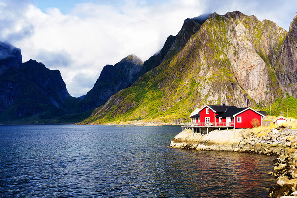 Известная туристическая достопримечательность Хамной рыбацкая деревня на Лофотенских островах, Норвегия с красными и желтыми домиками рорбу. Спокойная, размытая вода - Фото, изображение