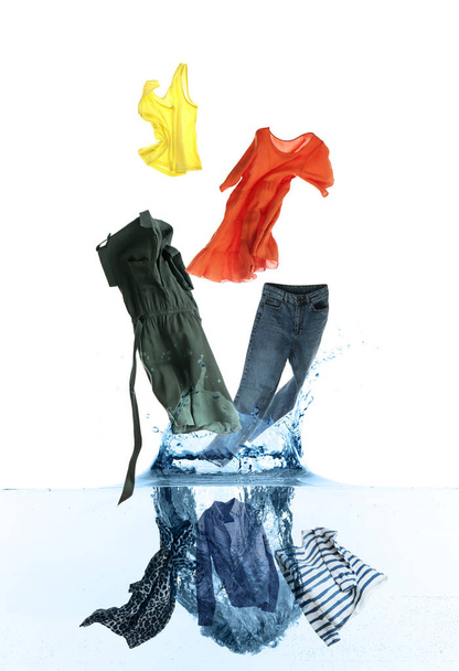 Different clothes falling into water against white background - Foto, Bild