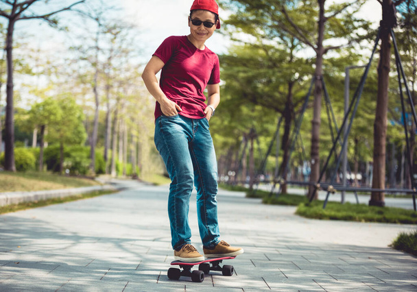 Asian woman skateboarder skateboarding in modern city - 写真・画像