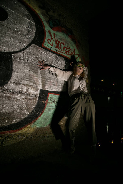 Female at night with a graffiti background. Low key - Zdjęcie, obraz
