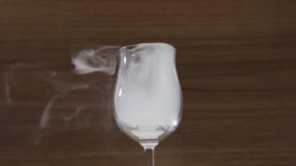 smoke flies away from wineglass on brown background closeup - Felvétel, videó