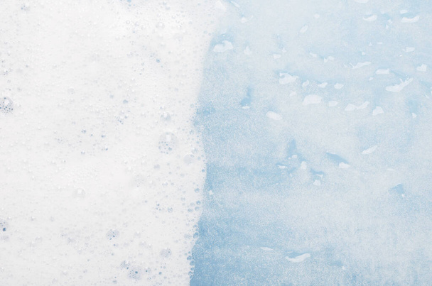 Fehér hab a kék víz felső nézet háttér. Szappanos folyadék fehér buborékokkal makró. Mousse textúra, hófehér hab. Zuhanyzó zselé hab közelkép. Háztartási mosószer, mosószer vízben történő feloldása. - Fotó, kép