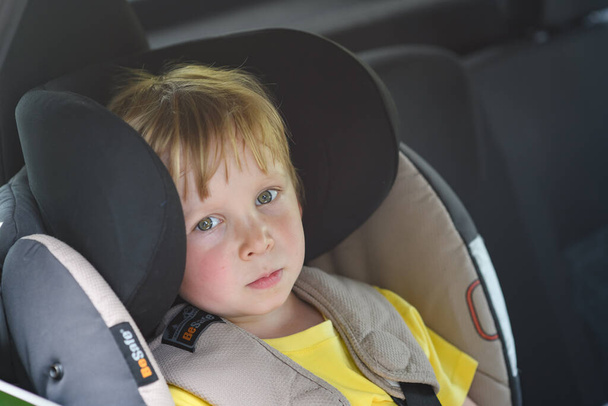 Portrait of cute toddler boy sitting in car seat. Child transportation safety - Photo, Image