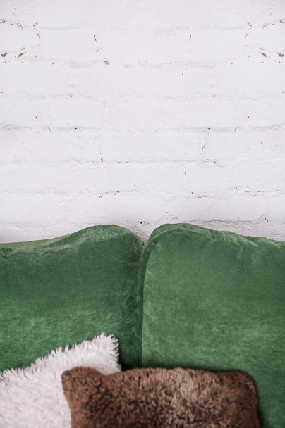Κενό λευκό τούβλο τοίχο με μαξιλάρια στον πράσινο καναπέ. Προσομοίωση για σχεδιασμό - Φωτογραφία, εικόνα
