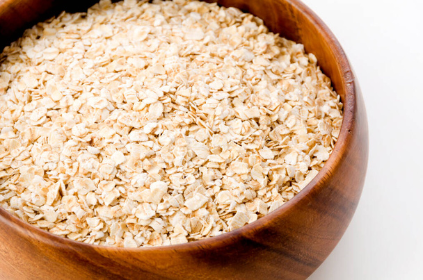 Oatmeal in a wooden round bowl on white background - Photo, Image