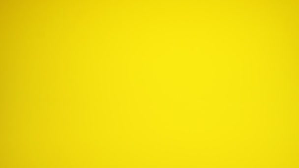 Ciliegie rosse rotolando giù su sfondo giallo. - Filmati, video