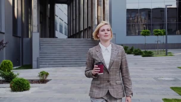 Confident blonde woman goes to the car with coffee. The director of the company goes to a meeting. Well dressed. - Footage, Video