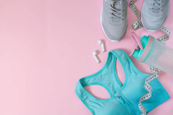 Sprzęt sportowy i odzież dla kobiet. Płaskie układanie obuwia sportowego, butelki, stanika, słuchawek i taśmy pomiarowej - Zdjęcie, obraz