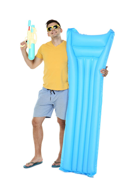 Young man with inflatable mattress and water gun on white background - Foto, immagini